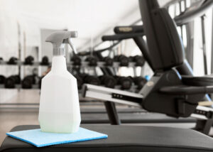 Spray de limpieza en un gimnasio con máquinas de ejercicio